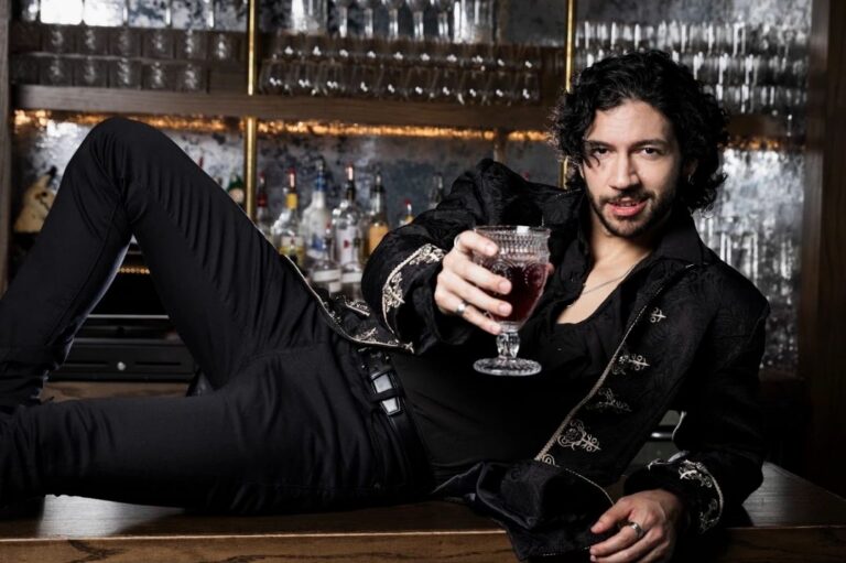 Performer dressed as Dracula holding a cocktail in a theatrical bar setting